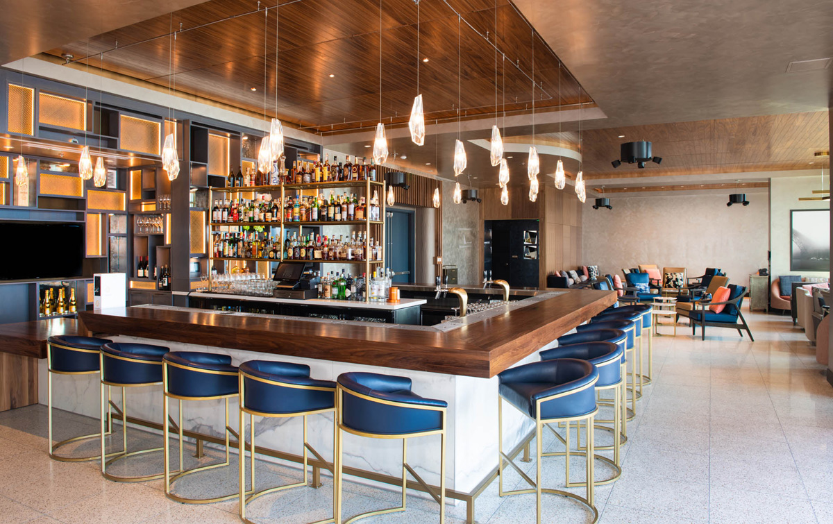a wide bar with blue stools and a wooden counter